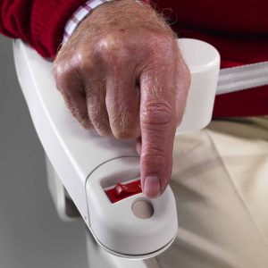 Close up of a finger reaching for a red power rocker switch located on the underside of a stairlift armrest.